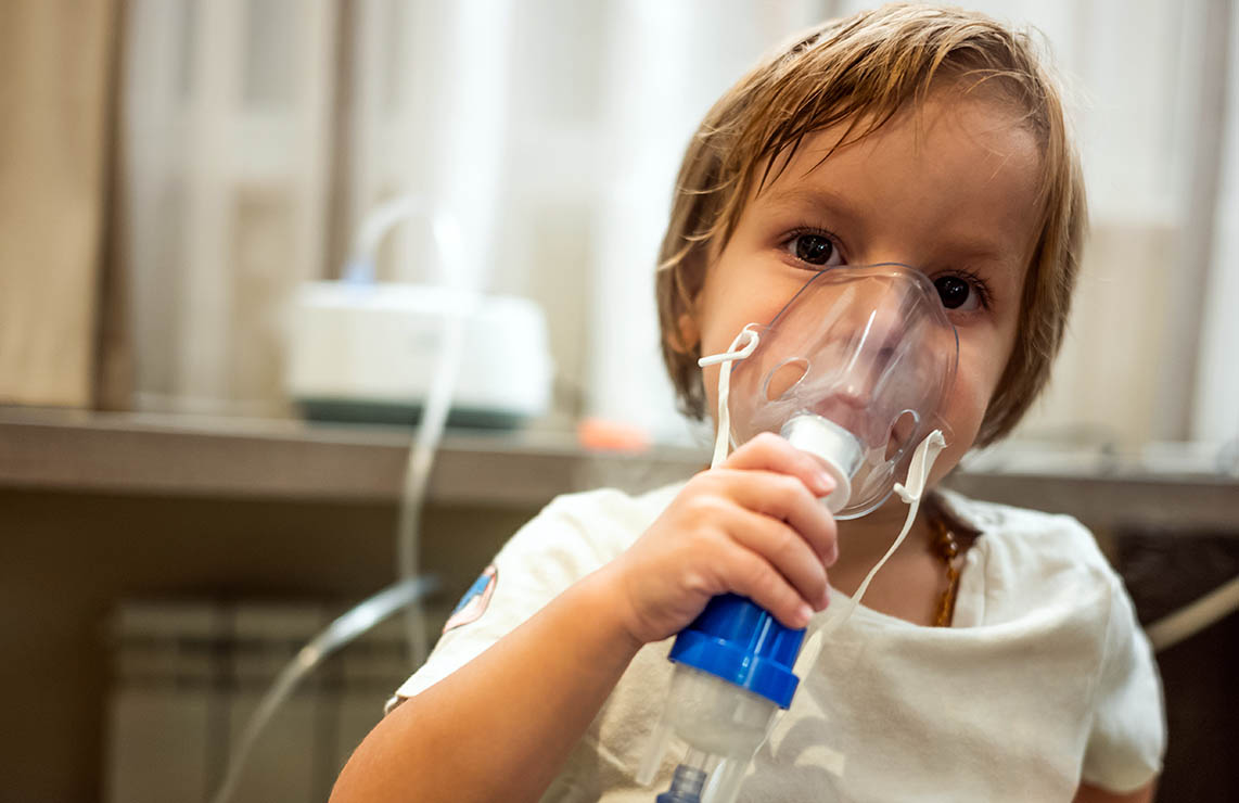 Young child holding breathing apparatus over nose and mouth Young child holding breathing apparatus over nose and mouth