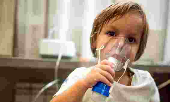Young child holding breathing apparatus over nose and mouth
