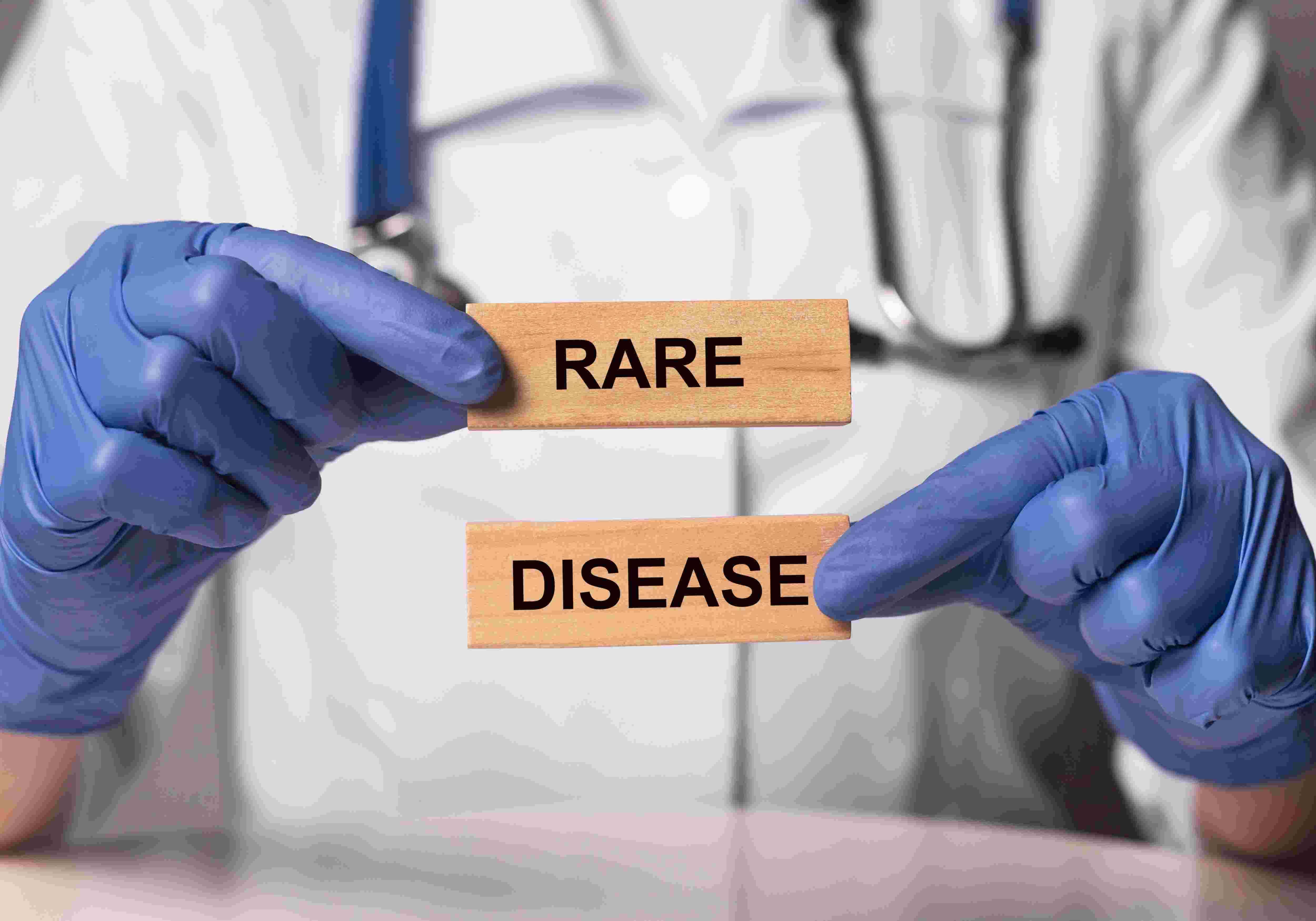photo of doctor with blue medical gloves holding small 'rare disease' sign