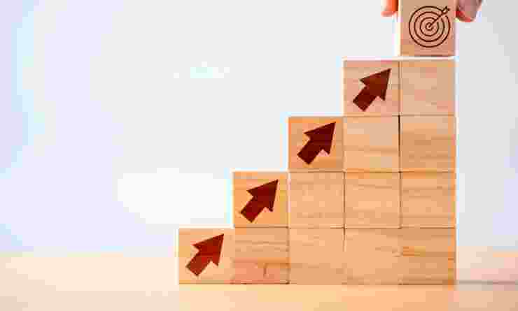Stacked wooden blocks with arrows pointing upwards to indicate progress and target