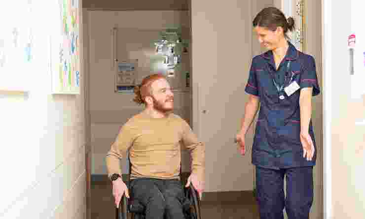 photo of: male disabled person in wheelchair greeted and speaking to clinican at S2 clinic both smiling