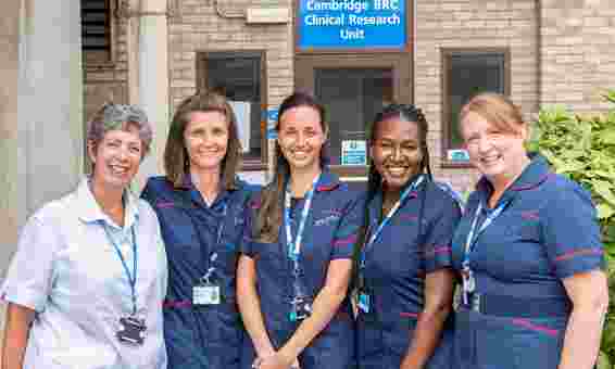 From left to right, Gillian, Dani, Barbara, Aisha and Emma from our clinical team all smiling in nursing uniform outside our Clinical Research Unit building 